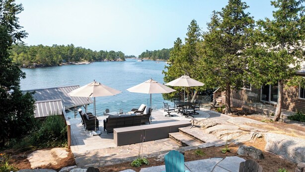 A deck with outdoor furniture overlooking a lake, surrounded by trees. - Richard's Island Pointe au Baril, in the sought after outer islands (Pointe au Baril)