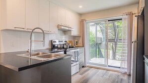 Een moderne keuken met een groot eiland, roestvrijstalen apparatuur en een schuifdeur naar een balkon.