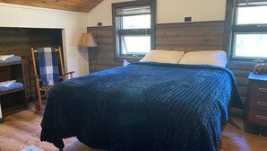 Ein Schlafzimmer mit einem Bett, einem Nachttisch, einer Lampe, einem Sessel und einem Regal.