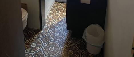 Um banheiro com banheira, pia, janela e piso estampado.