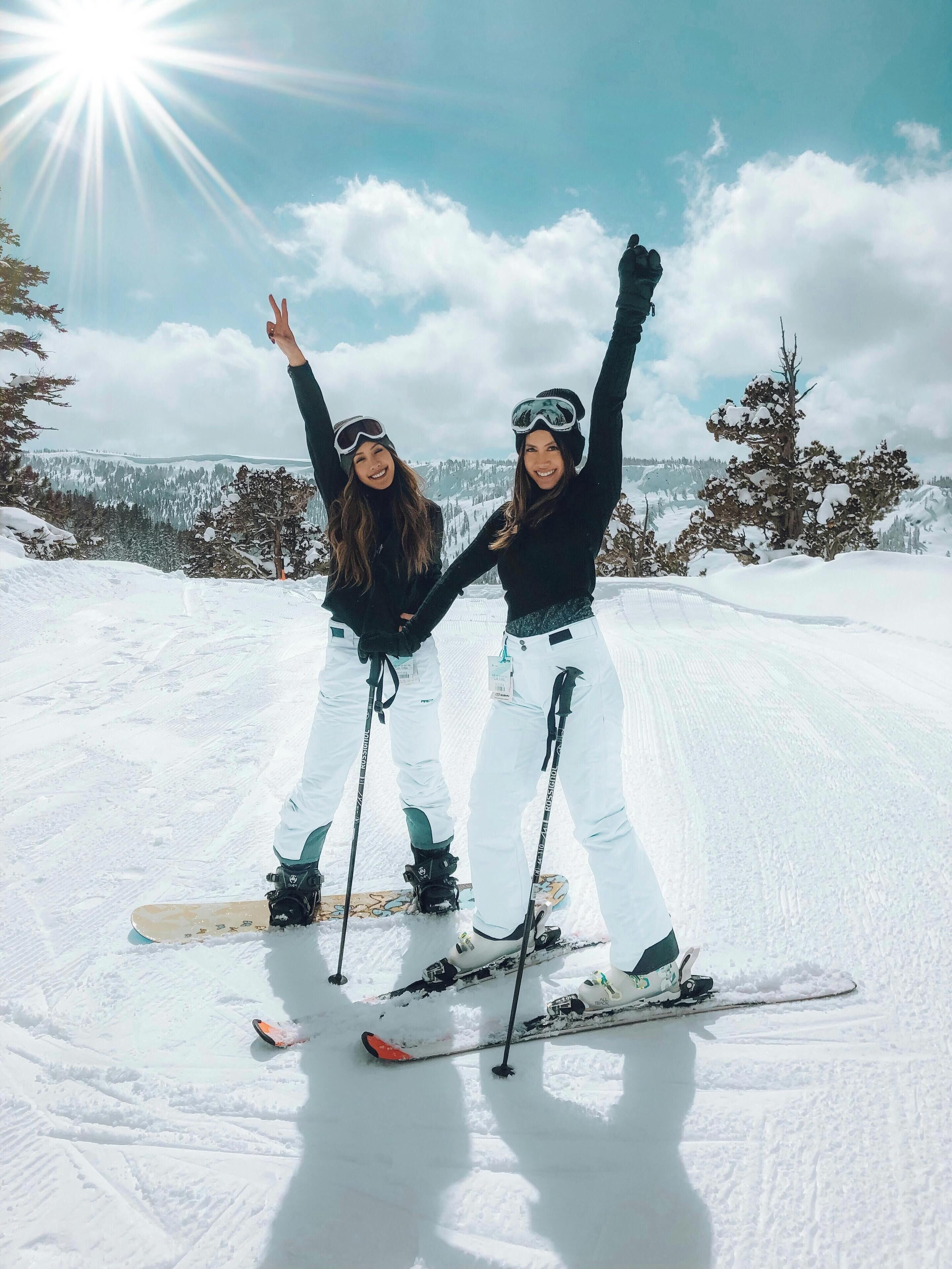 Zwei Personen auf Skiern vor einer verschneiten Berglandschaft.