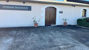 A building with a sign reading "DOMAINE BEAUSÉ JOUR" and a large wooden door. There are two potted plants in front of the door. - Les Fossiles - 4/6 people (Noyers-sur-Cher)