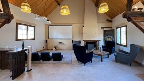 A spacious loft-style living room with high ceilings, exposed wooden beams, and a fireplace. There are several seating areas with modern sofas and a coffee table. - Gite sleeps 18 (Noyers-sur-Cher)