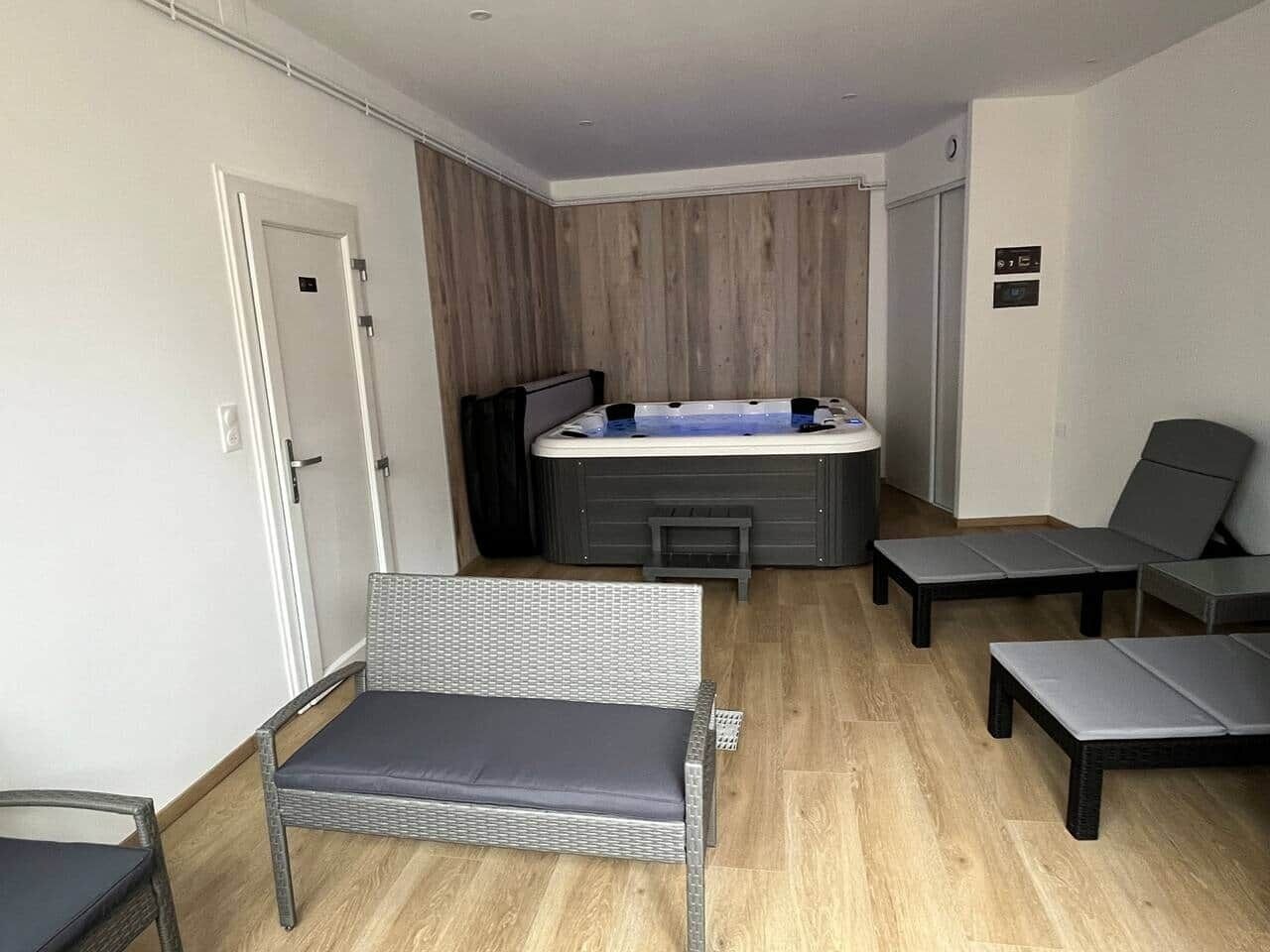 A modern room with a hot tub, a wicker sofa, and two lounge chairs.