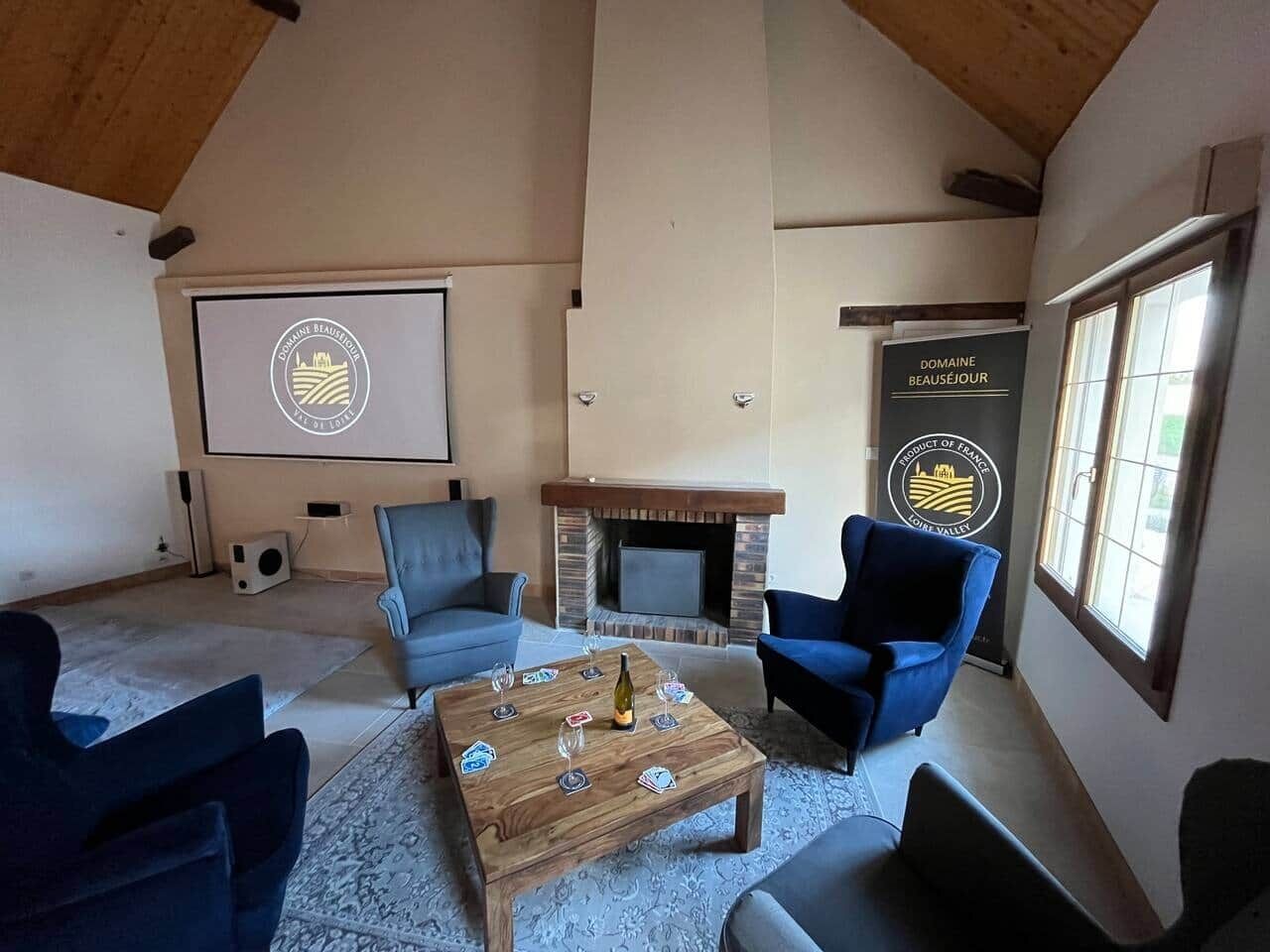 Un salon chaleureux avec une cheminée, des sièges confortables et un écran de projection.