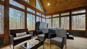 Une terrasse en bois avec des meubles en osier, une table en verre et un jacuzzi.