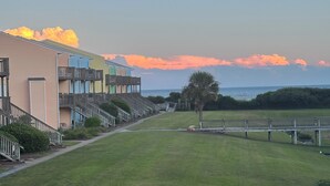 Un hôtel situé en bord de mer, doté de nombreux balcons, d’une pelouse verdoyante et d’un sentier pédestre.