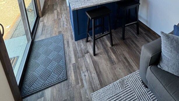 Een moderne keuken met een groot eiland, houten balken in het plafond en uitzicht op het groen.