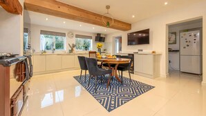 Una cocina moderna con comedor, vigas de madera, televisor y refrigerador.