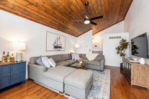 A living room with a wooden ceiling, a sofa, a coffee table, a TV, and a cabinet.