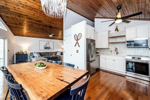A modern kitchen with white cabinets, stainless steel appliances, and a wooden dining table.
