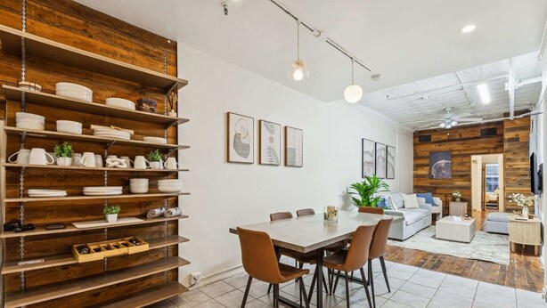 A modern kitchen with wooden shelves, a dining table, and chairs. - Spacious 3BR Flex 4 with Washer & Dryer in NoMad (New York)