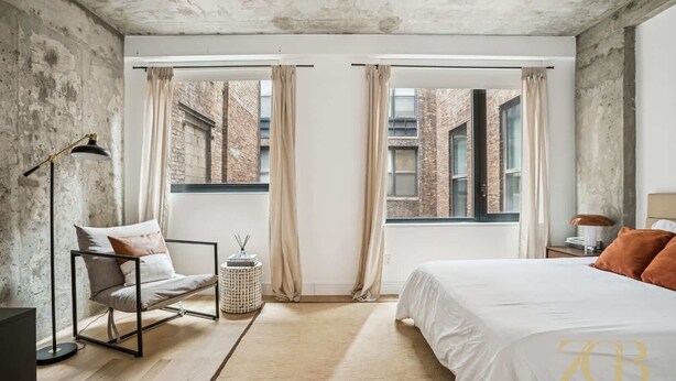 Una camera da letto con un letto, una sedia, una lampada e un tavolino.