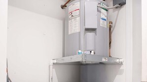 Una lavanderia con due lavatrici Whirlpool e uno scaldabagno.