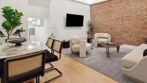 Ein modernes Wohnzimmer mit Backsteinwand, Flachbildfernseher und Essbereich mit Tisch und Stühlen.