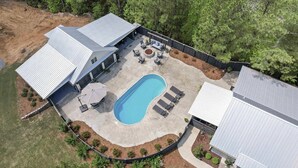A residential property with a swimming pool, outdoor seating, and a covered patio area. - 5 Minutes from Lake / Cozy Mountain Home with a Heated Pool & Pool House! (Grant)