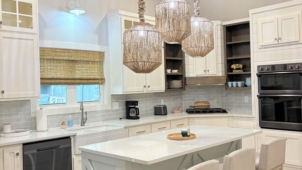 A modern kitchen with a large island, bar stools, a dishwasher, and a double oven. - 5 Minutes from Lake / Cozy Mountain Home with a Heated Pool & Pool House! (Grant)