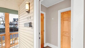 Une entrée d’habitation avec une porte en bois, une boîte aux lettres et un porche doté d’une balustrade.