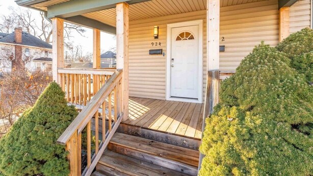 Une maison en bois avec un porche, une porte blanche et une boîte aux lettres.
