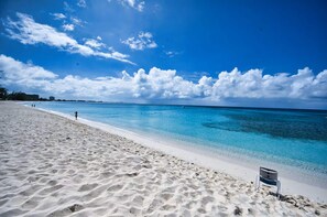 A beach with clear turquoise water, white sand, and a few people walking. - Beach Paradise 1 Bedroom with Pull Out Sofa (West Bay)
