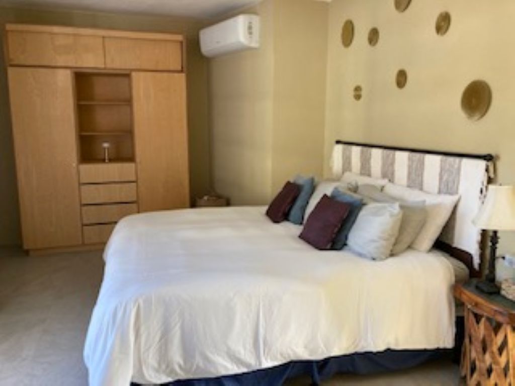 Une chambre à coucher comprenant un lit, une armoire, une table de chevet et un climatiseur fixé au mur.