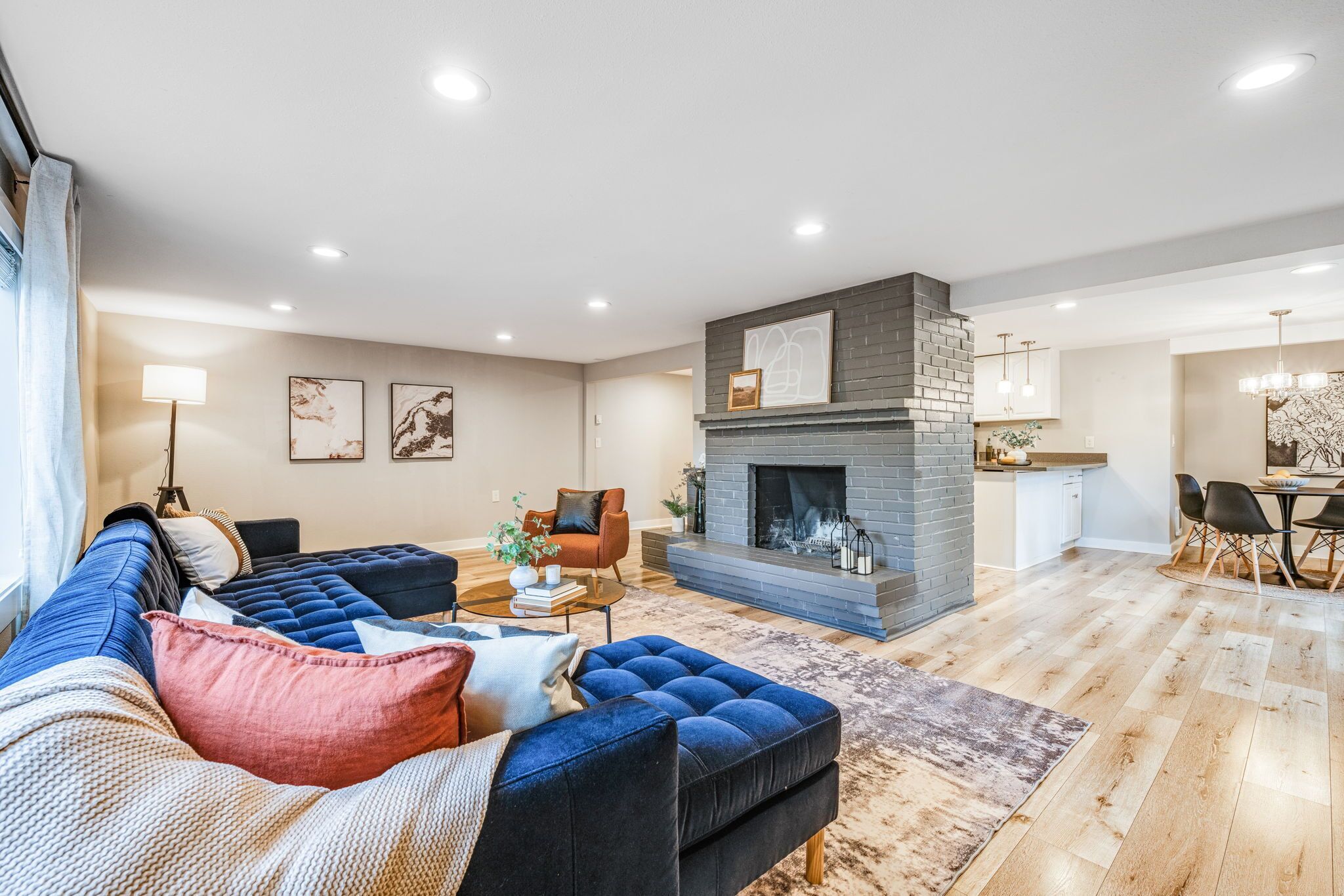 A modern living room with a sectional sofa, a fireplace, and a dining area.