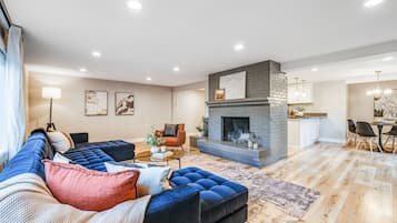 A modern living room with a sectional sofa, a fireplace, and a dining area.