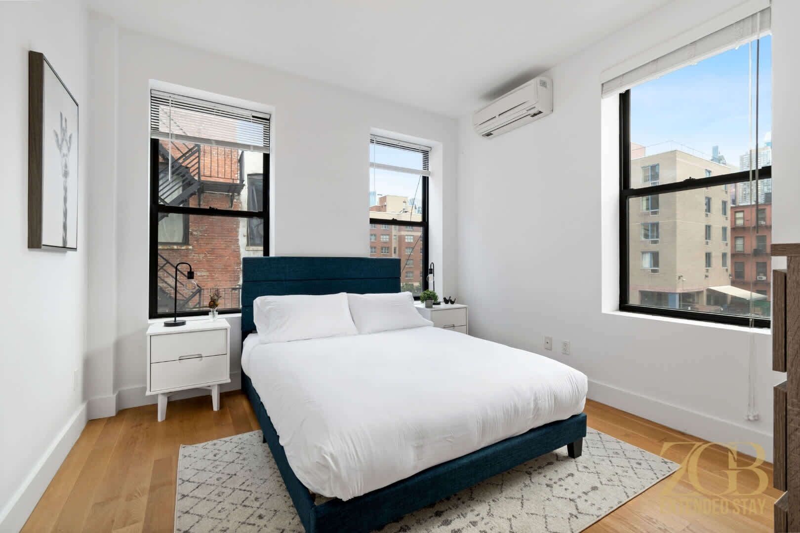 Quarto com cama, duas mesas de cabeceira, uma janela e ar condicionado.