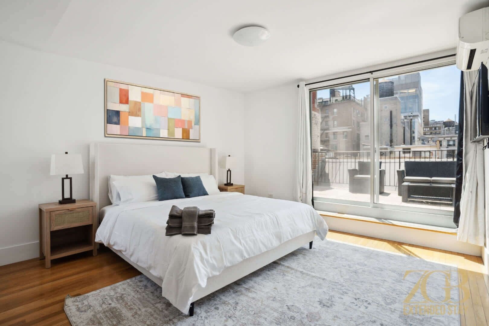 Un dormitorio moderno con una cama grande, vistas a la ciudad y una decoración minimalista.
