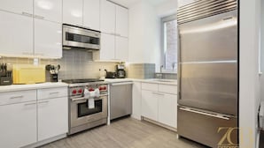 A modern kitchen with white cabinetry, a built-in oven, a microwave, a stove, and a stainless steel refrigerator. - Fully Furnished PH Duplex with Private Outdoor Space (New York)