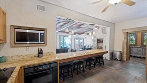 A kitchen with a central island, a microwave, a dishwasher, and a ceiling fan. - Guadalupe Riverfront | Private Hot Tub | Sleeps 14 (New Braunfels)