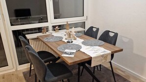 Ein Esstisch mit vier Stühlen, ein Fenster mit Jalousien und eine Heizung an der Wand.