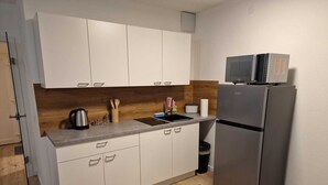 Eine moderne Küche mit weißen Schränken, einem Edelstahlkühlschrank, einer Mikrowelle und einem Spülbecken.