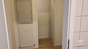 Ein Flur mit Holzboden, einem Heizkörper und einer Tür zu einem anderen Raum.