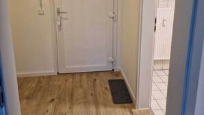 Ein Zimmer mit Holzboden, einer weißen Tür und einer kleinen Matte im Eingangsbereich.