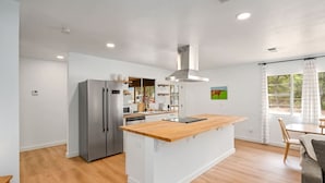 Een moderne keuken met een centraal eiland, roestvrijstalen apparatuur en een eetgedeelte met uitzicht.