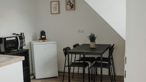 Et kompakt køkken med mikroovn, køleskab og spiseplads med bord og stole.