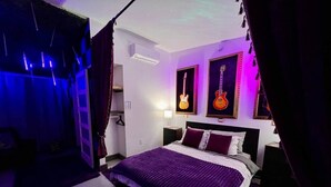 A bedroom with a large bed, purple bedding, and two guitars on the wall. - Purple Rain/Pop Culture 2bd 2bth Luxury Pool Hot Tub (Lutz)
