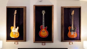 A hotel room with three framed guitars on the wall, a bed with white bedding, and a bedside table with a lamp. - Purple Rain/Pop Culture 2bd 2bth Luxury Pool Hot Tub (Lutz)