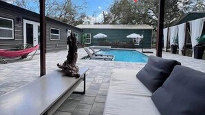A poolside area with a white sofa, a bench, and a statue. - Purple Rain/Pop Culture 2bd 2bth Luxury Pool Hot Tub (Lutz)