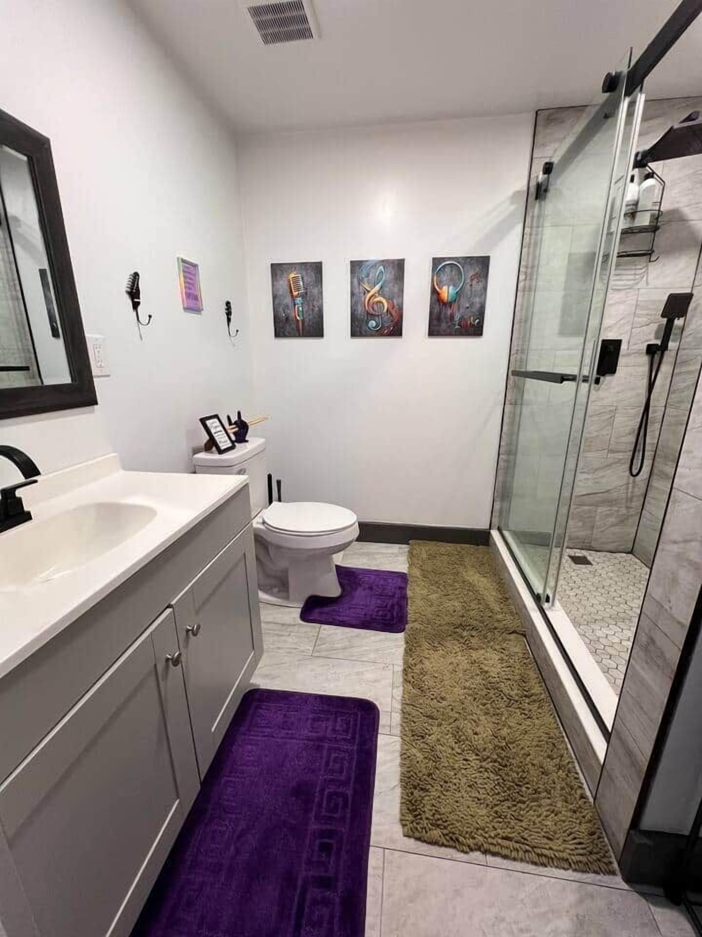 A modern bathroom with a glass shower enclosure, a white sink, and a toilet.