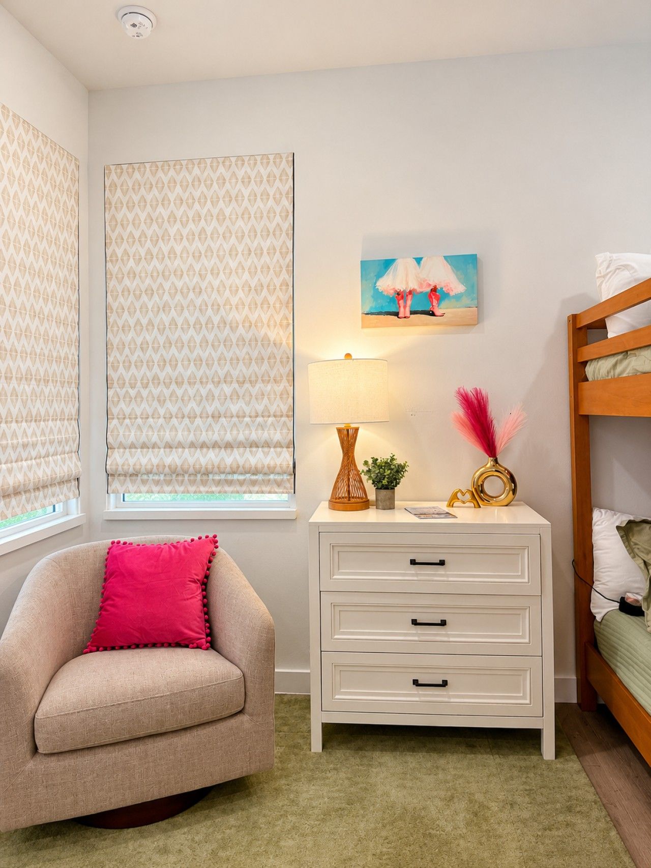 Un dormitorio con una cama litera, una mesita de noche con lámpara, una silla y un cuadro en la pared.