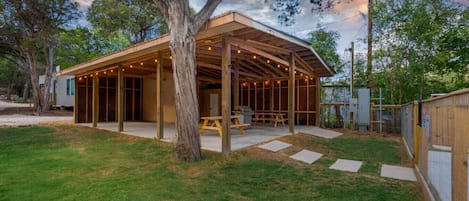 A covered outdoor patio with a wooden deck, a picnic table, and string lights.