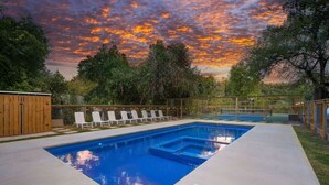 A rectangular swimming pool with a clear blue water surface, surrounded by a concrete deck. - Hill Country Cottage | 1BR King | Pool + Hot Tub | Pets Welcome (New Braunfels)