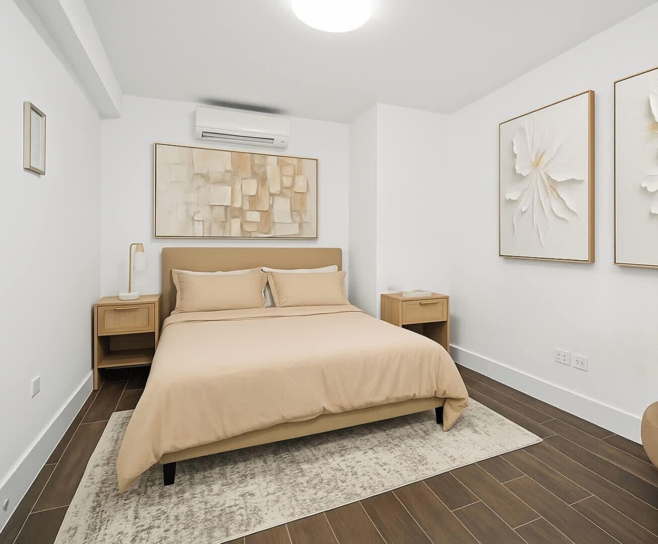 A modern bedroom with a bed, two bedside tables, a wall-mounted air conditioner, and abstract wall art.