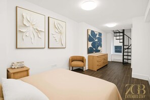 Ein Schlafzimmer mit einem Bett, einem Schminktisch, einem Sessel und Bildern an den Wänden.