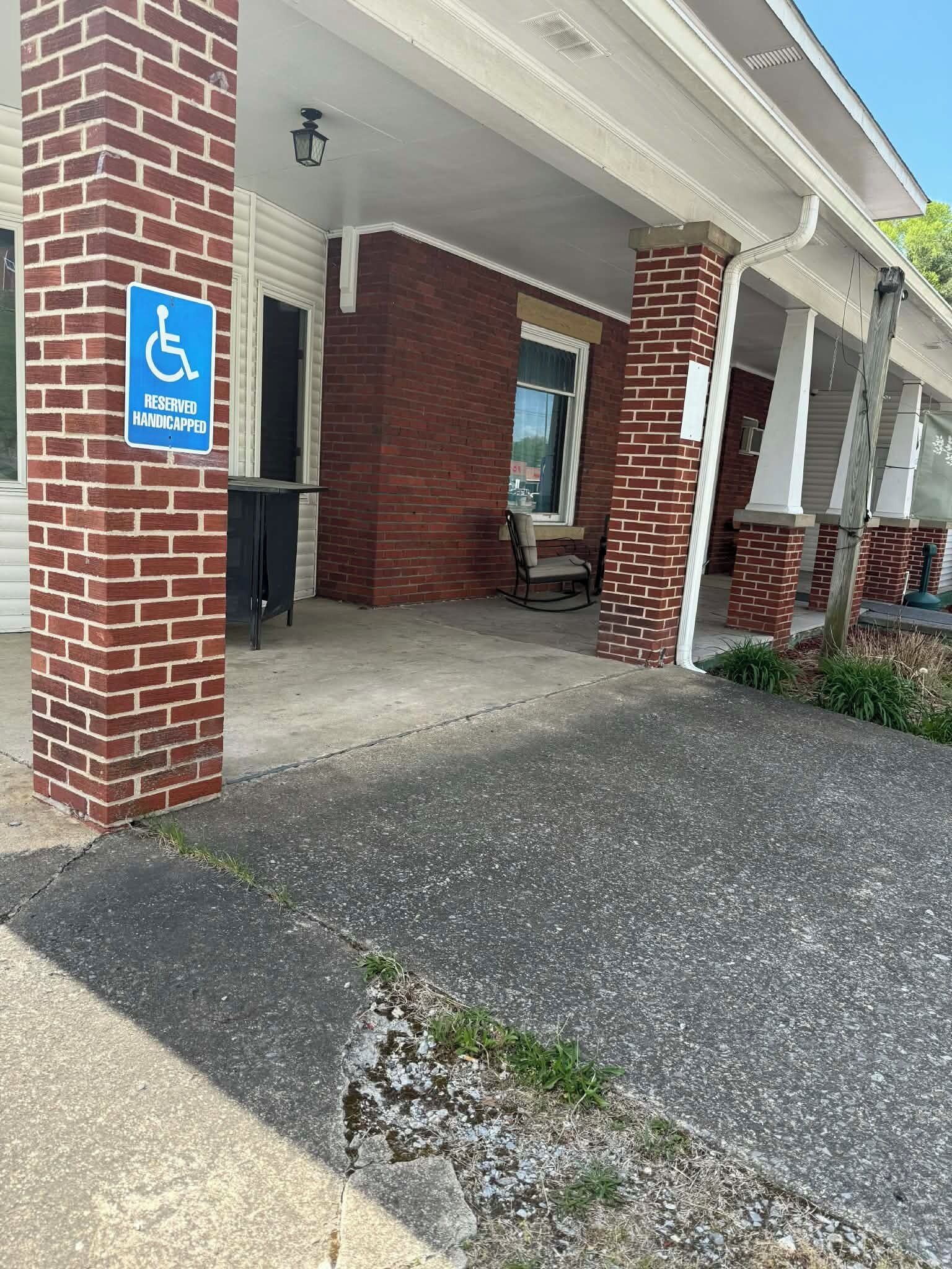 Een gebouw met een bakstenen gevel, een overdekte veranda en een toegang voor mensen met een handicap.