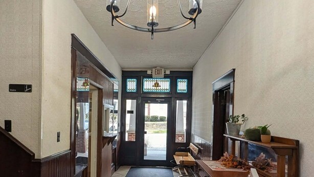 Un pasillo con candelabro, un banco y una mesa de recepción.