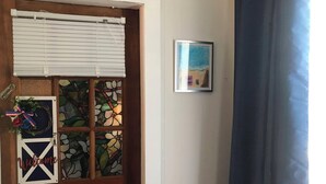 Een houten deur met een glas-in-loodraam, een bord met een welkomstboodschap en een lijst met een afbeelding aan de muur.