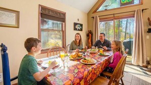 A dining table with a family of four seated around it, enjoying a meal. - Family-Friendly Home w/ Hot Tub • Fire Pit• Games (Swanton)